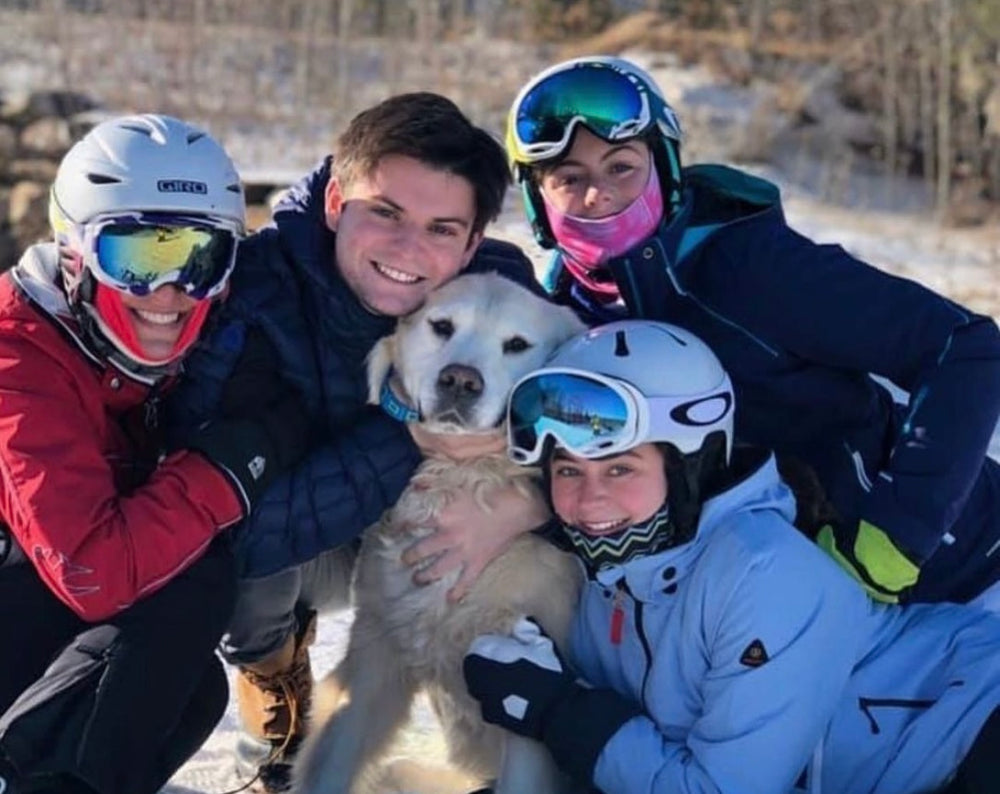 Image shows a family in winter gear hugging their dog in the middle. Image demonstrates the time of year antifreeze poisoning in dogs is prevalent. 