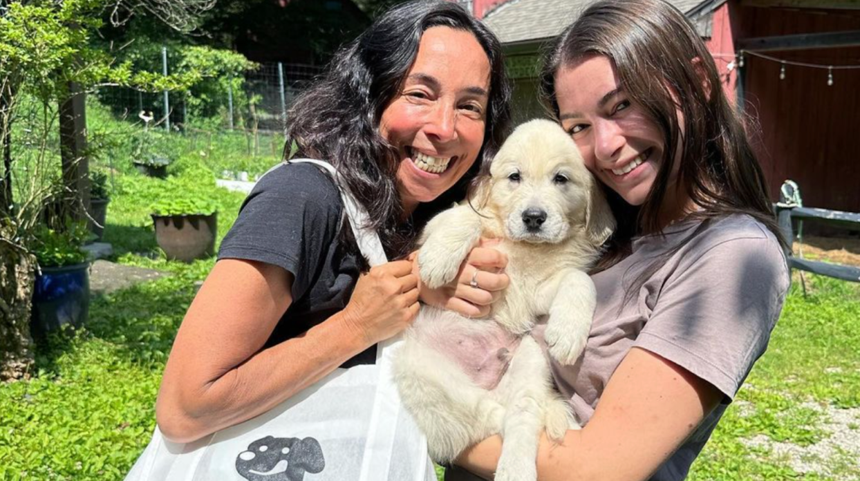 Two dog owners pose with their adorable puppy.