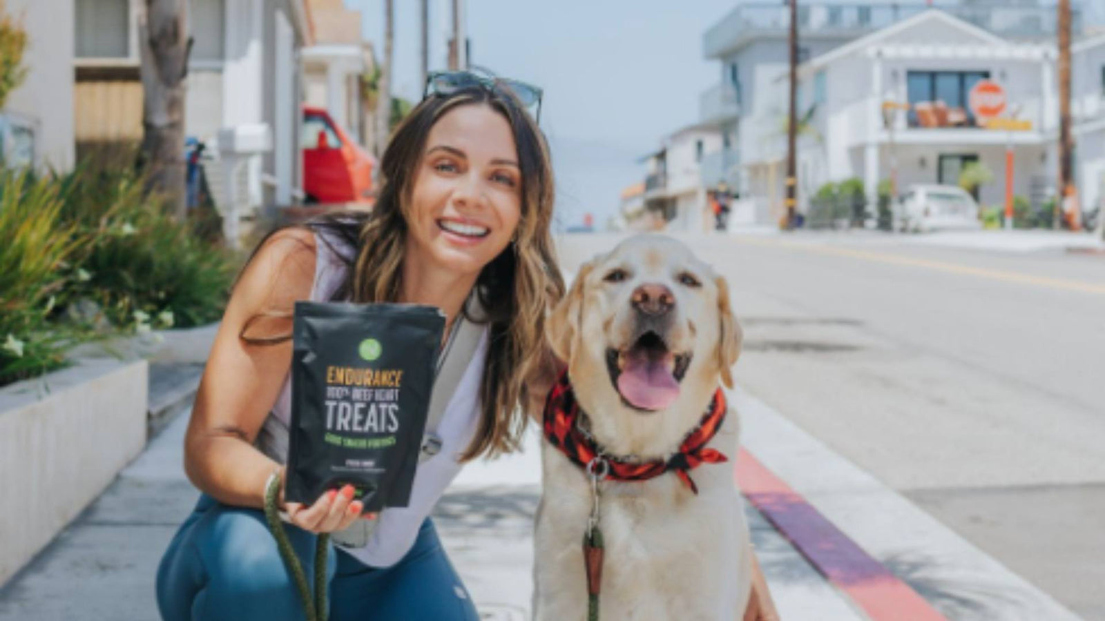 A woman and her dog stand side by side. The woman is holding Get Joy dog treats. This photo is demonstrating mindfulness and pet wellness.