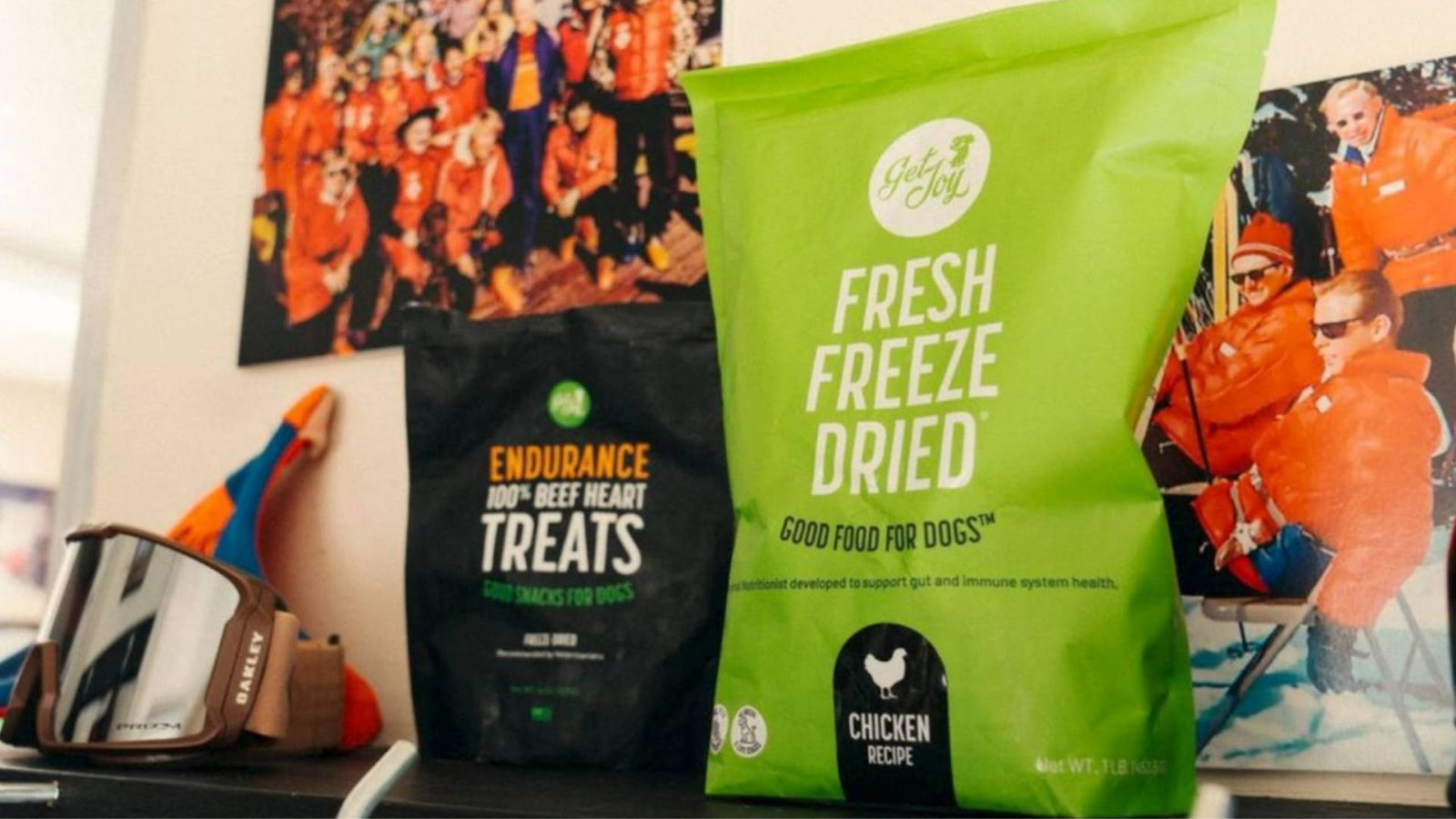 A green bag of Get Joy's fresh freeze dried dog food is displayed next to a black bag of Get Joy's healthy dog treats.